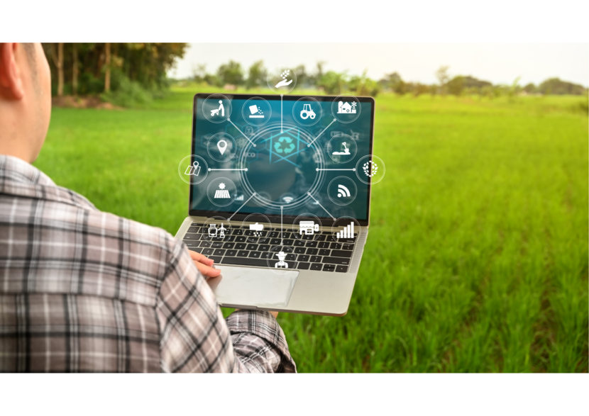 man staat op een akker en houdt een laptop vast waarop icoontjes van smart farming op staan