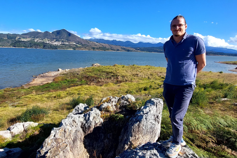 Biodiversity Counsellor Emiel standing on grass with a lake and mountains in the back