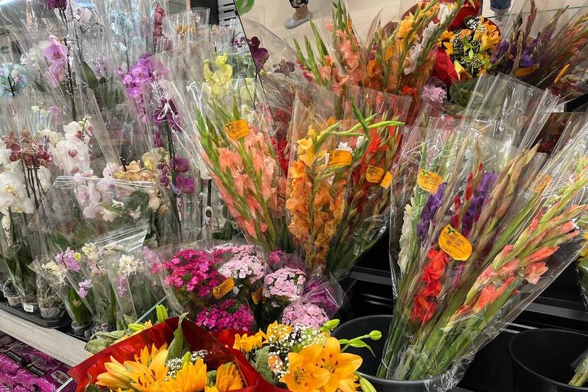 diverse types of cut flowers in production sleeves at a display in a retail market