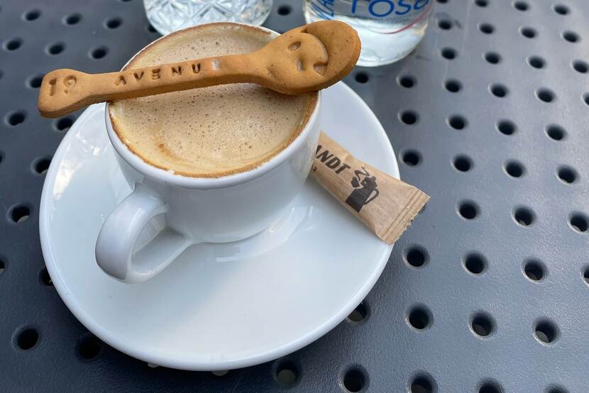 Close-up picture of a new, edible spoon laid across the rim of a coffee cup filled with capuccino