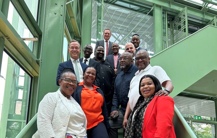 People stand posing for a photo on a staircase surrounded by green iron structures